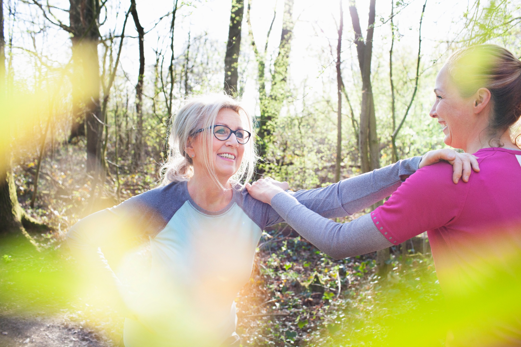 Zwei Frauen lachen miteinander im sonnigen Frühlingswald